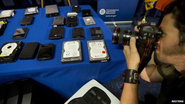 A photographer takes photo of seized hard drives that contain child pornography following a news conference to announce the arrest of 71 individuals for sharing child pornography online in New York 21 May 2014