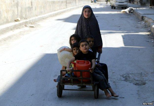 A girl pushes four children on a cart in the al-Shaar neighbourhood of Aleppo - 14 May 2014