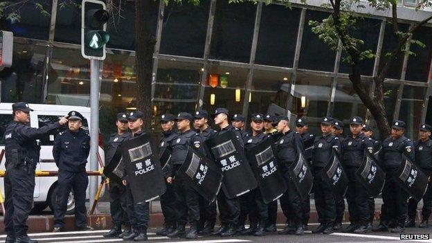 Policemen with riot gear gather as they block a street leading to the site of an explosives attack, in downtown Urumqi, Xinjiang Uighur Autonomous Region, 23 May 2014