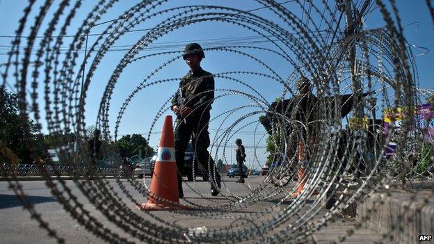 Thai soldiers stand guard at checkpoint near "red shirt" encampment, Bangkok (22 May)