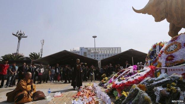 Buddhist monks pray in front of offerings and wreathes for the victims of a knife attack last Saturday, at Kunming Railway Station in Kunming, Yunnan province 7 March 2014. At least 29 people were killed and police shot dead four of the attackers.