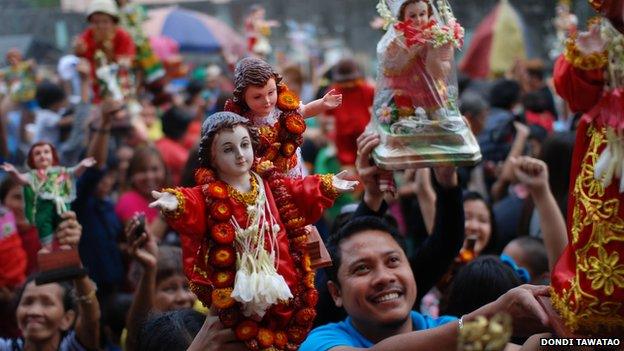 Catholics hold up statuettes of Jesus