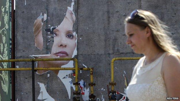 A woman and her daughter walk past a torn poster of Ukrainian politician and presidential candidate Yulia Tymoshenko in Luhansk, eastern Ukraine, May 16