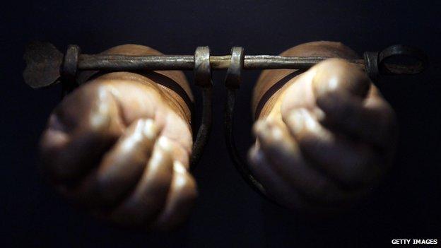 A photograph of a pair of hands in manacles.