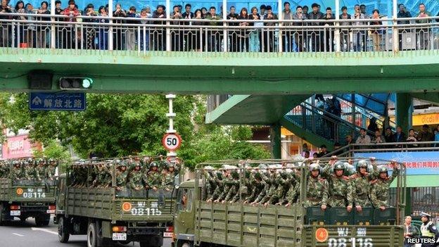 Paramilitary policemen ride on trucks during a parade in central Urumqi (23 May)