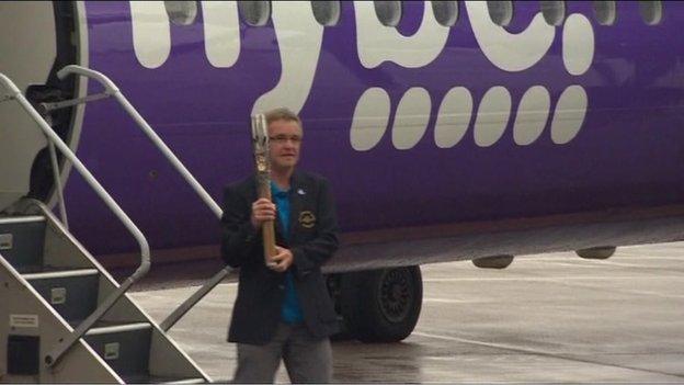 Man carrying Queen's Baton off plane at Cardiff Airport