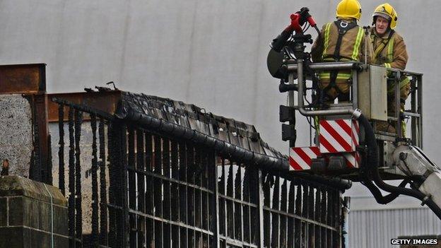 Firefighters beside burnt-out building