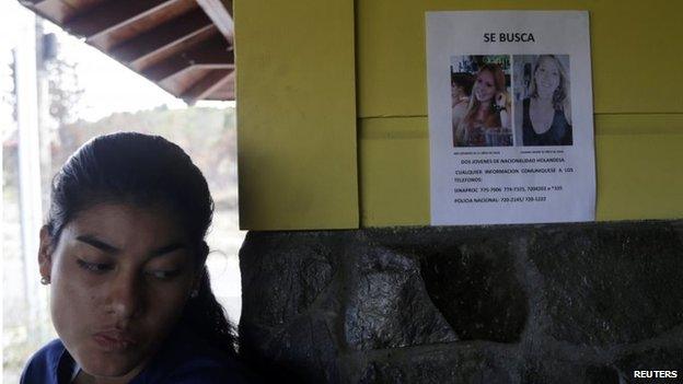 A woman stands next to a missing person flyer showing pictures of two missing Dutch women on a wall in the town of Boquete on 12 April, 2014