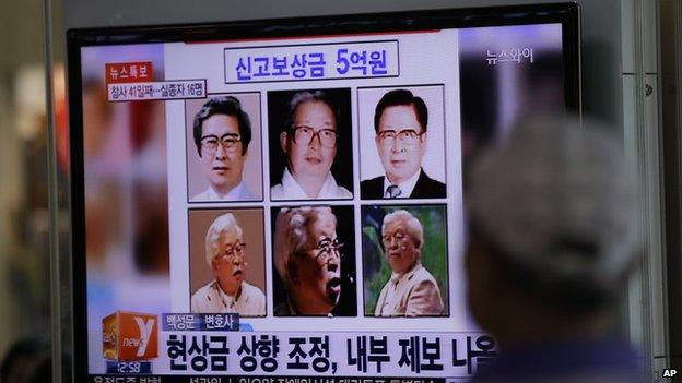 A man watches a TV news program on the reward poster of Yoo Byung-eun at the Seoul Train Station in Seoul, South Korea, Monday, 26 May 2014.