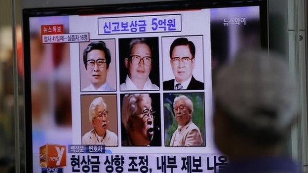 A man watches a TV news program on the reward poster of Yoo Byung-eun at the Seoul Train Station in Seoul, South Korea, Monday, May 26, 2014.