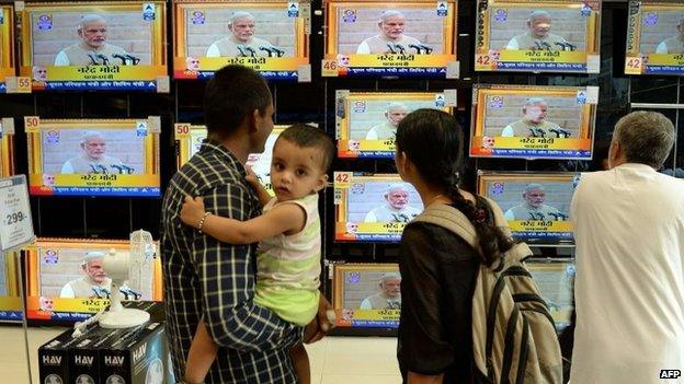 Residents watch a bank of televisions featuring images of Narendra Modi taking his oath as India"s Prime Minister in New Delhi at a multi brand electronic showroom in Mumbai on on May 26, 2014