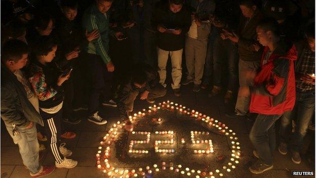 Residents light candles to form the date of 'May 22' and a heart figure as they mourn the victims who were killed during a bomb attack in Urumqi, Xinjiang, on 23 May