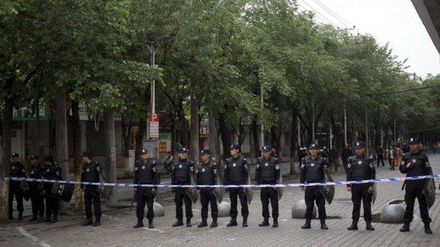 Policemen stand guard near the road leading to the site of Thursday's explosion in Urumqi, China's northwestern region of Xinjiang, Friday, 23 May.