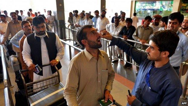 In this photograph taken on May 20, 2014, a Pakistani health worker administers polio vaccination drops to a traveller at the Peshawar International Airport in Peshawar.