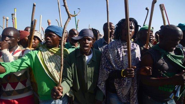 Striking miners hold sticks as they dance and sing during a protest against their labour conditions, in the Wonderkop stadium in Marikana, South Africa, on 14 May 2014