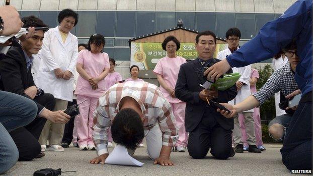 Officials kneel and bow as they apologise to victims outside a hospital in Jangseong, southwest region of Jeolla on 28 May.