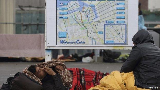 Afghan migrants rest under blankets in the courtyard at a food distribution centre