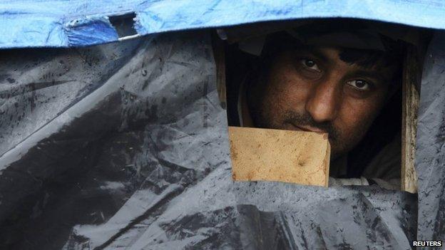 An Afghan migrant looks out the window of his makeshift shelter at the harbour in Calais