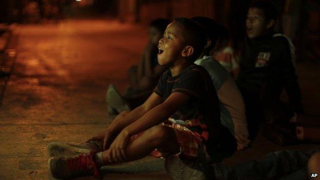 Children watch a friendly match between Honduras and Venezuela on TV on 5 March 2014