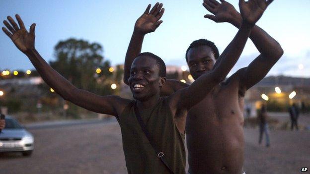 Sub-Saharan migrants react after scaling a metallic fence that divides Morocco and the Spanish enclave of Melilla