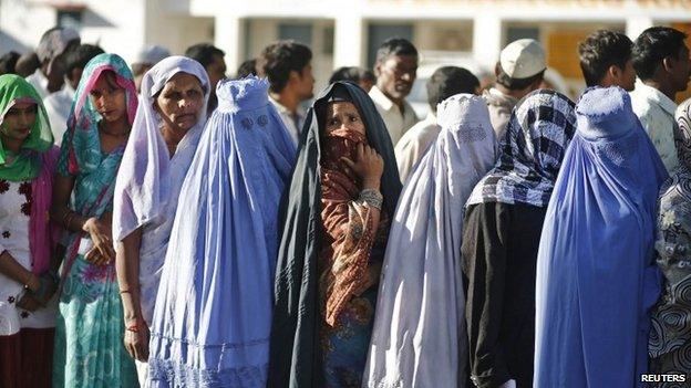 Muslim women, who were displaced by deadly religious strife last year, stand in a queue to cast their votes for the general election at a polling station in Palra village in Muzaffarnagar.