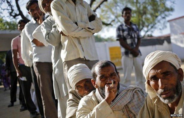 Muslim men, who were displaced by deadly religious strife last year, wait to cast their vote for the general election outside a polling station in Parla village in Muzaffarnagar district