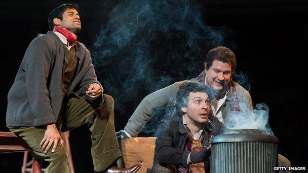 Characters in La Boheme, gathered around a brazier