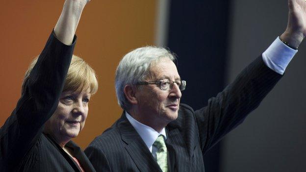 German Chancellor Angela Merkel (L) and former Prime Minister of Luxembourg, Jean-Claude Juncker (R) waving at a rally in Berlin on 5 April 2014