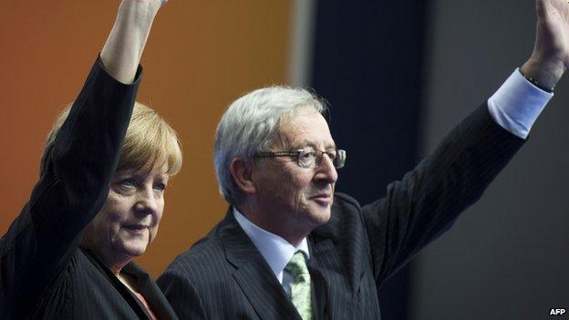 German Chancellor Angela Merkel (L) and former Prime Minister of Luxembourg, Jean-Claude Juncker (R) waving at a rally in Berlin on 5 April 2014