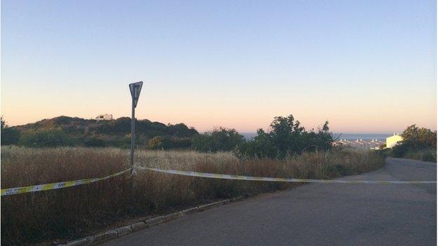 Police tape in front of an area of scrubland