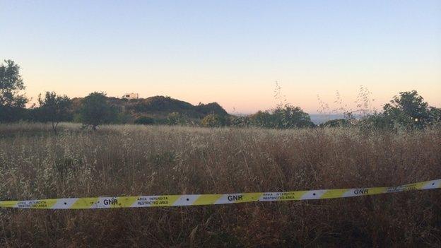 Police tape in front of an area of scrubland