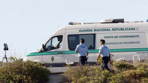 Two Portuguese police walking next to a parked police van