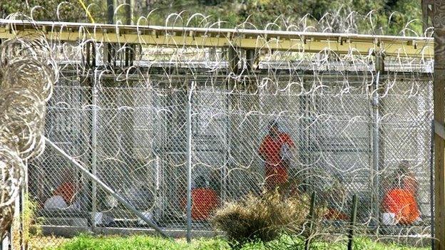 Dressed in bright orange coveralls, al-Qaida and Taliban prisoners sit in their chain-link cells at Camp X-Ray, where they are being held, at the U.S. Naval Base at Guantanamo Bay, Cuba, Sunday, Jan. 27, 2002