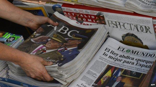 A woman arranges special editions of Spanish newspapers featuring a portrait of Spanish King Juan Carlos. Photo: 2 June 2014