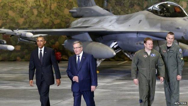 US President Barack Obama (left) and Poland's President Bronislaw Komorowski (2nd L) walk past an F-16 fighter upon Obama's arrival at Chopin Airport in Warsaw, 3 June 2014