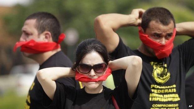 Federal police wearing T-shirts that read in Portuguese "SOS Federal Police" cover their mouths with bandanas in Rio de Janeiro on 7 May, 2014