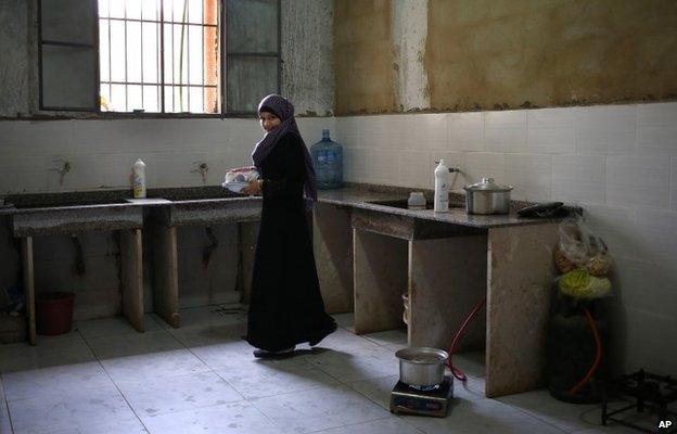 A Syrian woman carries plates in a kitchen at a centre for refugees in Kirbet Daoud, north Lebanon (29 May 2014)