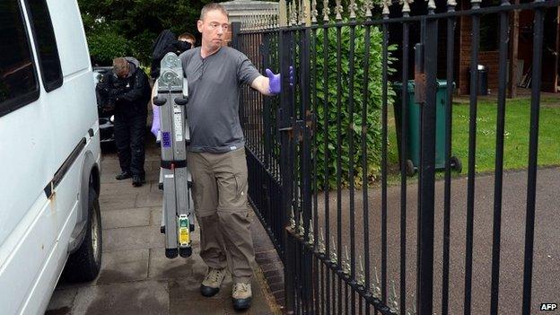 A police officer carries a ladder into the house of Altaf Hussain in London (3 June 2014)