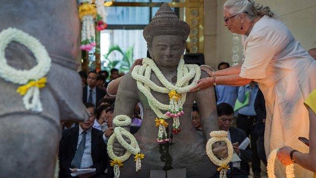 An assistant places traditional Cambodian crowns of flowers around the neck of the Balarama statue returned by Christie's auction house during an unveiling ceremony on 3 June, 2014 in Phnom Penh, Cambodia