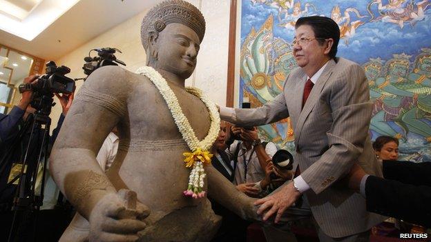 Deputy Prime Minister Sok An places a garland on an ancient artefact which are recently returned to the country during a ceremony at the Council of Ministers in Phnom Penh on 3 June, 2014