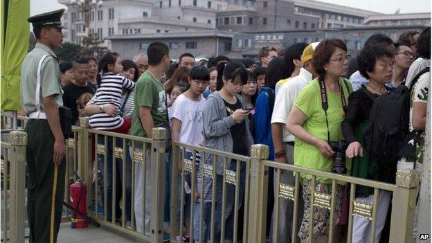 A Chinese paramilitary policeman watches over tourists on Tiananmen Square in Beijing, June 4