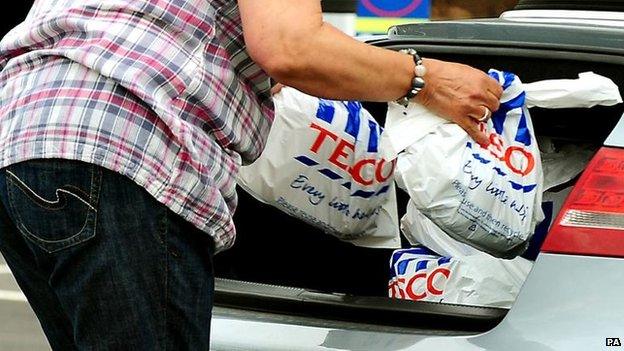 Shopper putting Tesco bags into a car