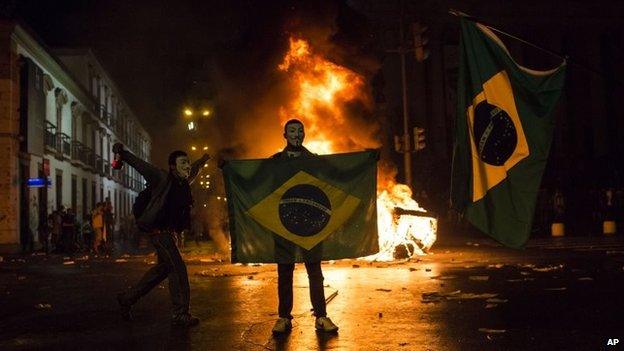 A demonstrator holds a Brazilian flag in front of a burning barricade during a protest in Rio de Janeiro on 17 June 2013