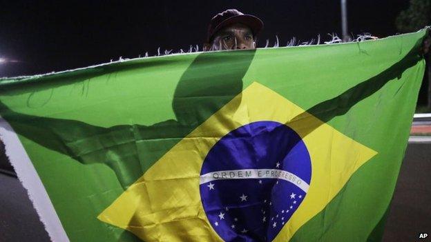 A member of the Homeless Workers Movement carries a Brazilian flag during a protest demanding better public services in Sao Paulo on 4 June, 2014