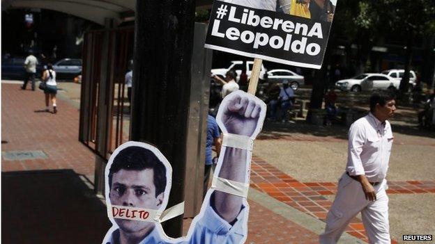 People walk past cardboard figures of jailed opposition leader Leopoldo Lopez with his mouth covered with the word "crime" during a gathering in support of him in Caracas on 4 June,, 2014