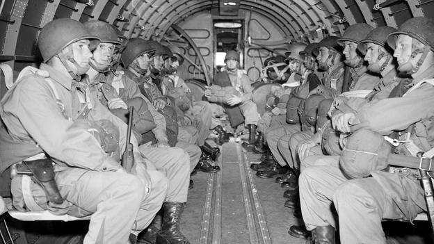 US paratroopers, heavily armed, sit inside a military plane as they soar over the English Channel en route to the Normandy French coast for the Allied D-Day invasion