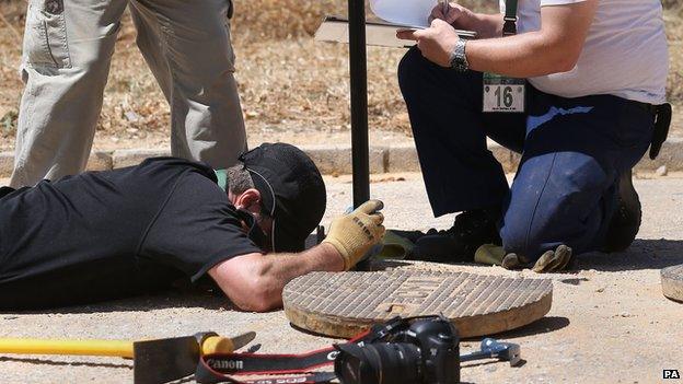 An officers looks inside a drain at the search site