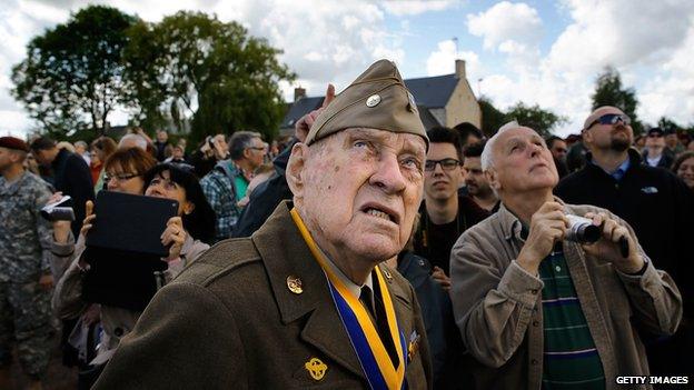 Veteran Raymond W. Sylvester, 95, watches as paratroop veterans drop into Picauville