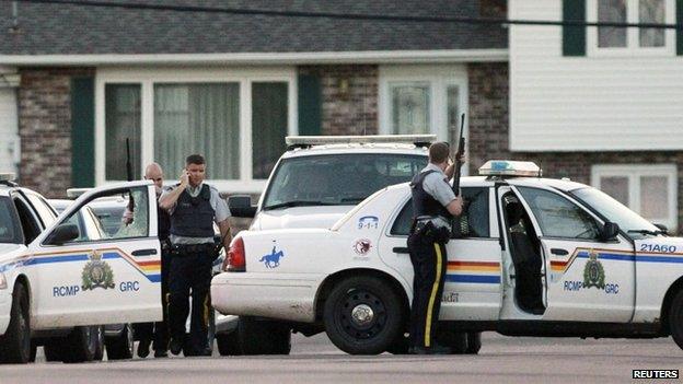 RCMP officers take cover behind their vehicles in Moncton, New Brunswick, on 4 June 2014