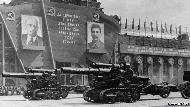 Heavy artillery on parade passing posters of Lenin and Stalin, 1947